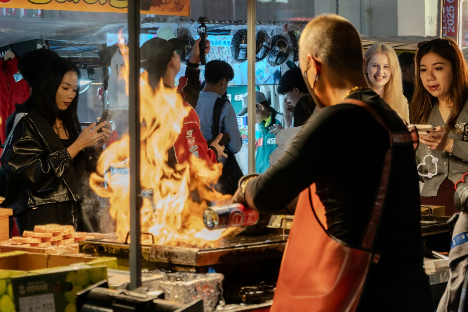 A vendor flame-cooking at a night street-food stall in Asia